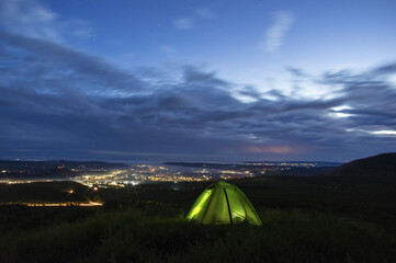 Obraz premium Morning landscape, tent against the background of sunrise and city lights on a hill in Ukraine