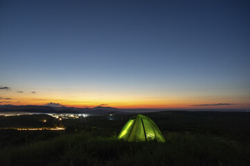 Fototapeta na wymiar Morning landscape, tent against the backdrop of the sunset and city lights on a hill in Ukraine