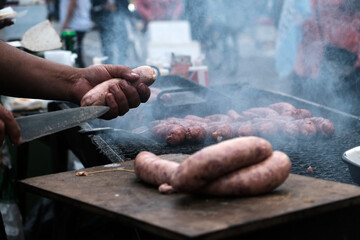 Argentine urban cook holding a chorizo