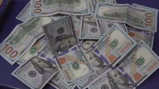 rain of 100 dollar bills on a table, 100 dollar bills are falling on a table full of 100 dollar bills.