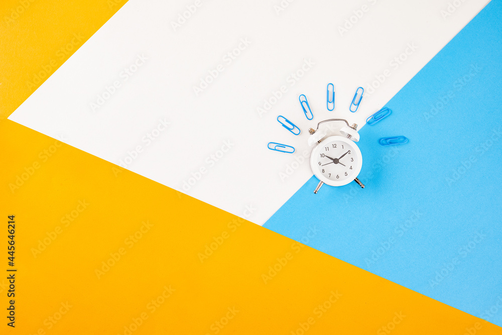 Poster alarm clock and paper clips isolated on colorful background