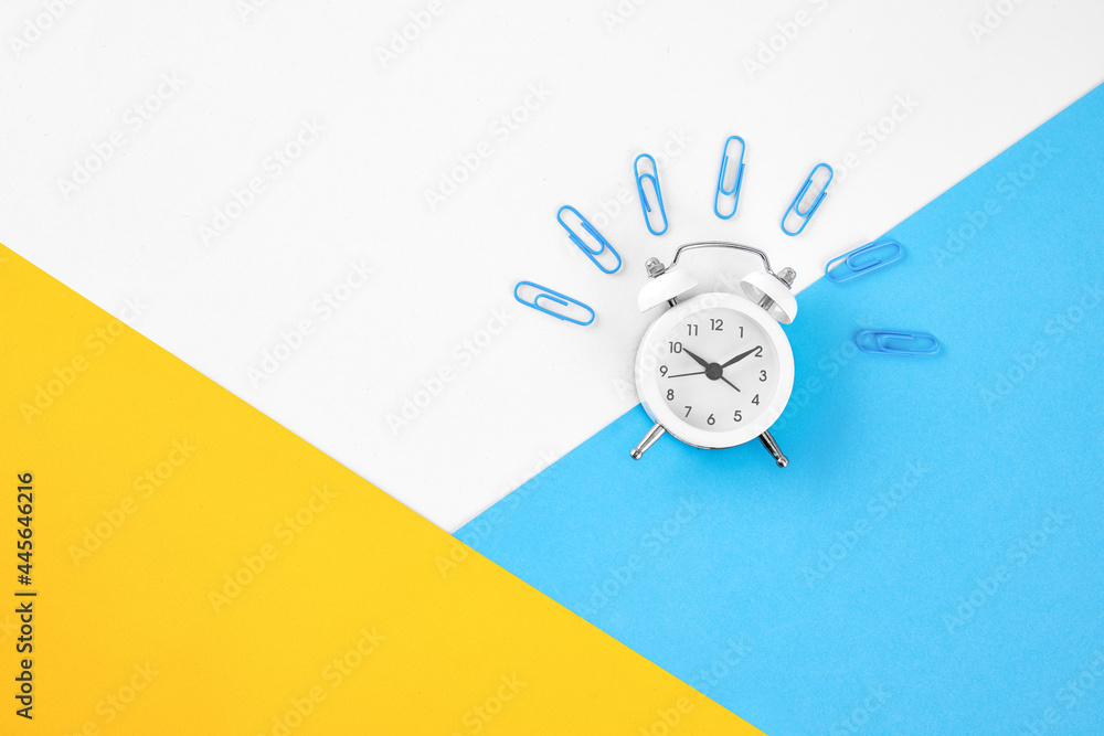 Poster alarm clock and paper clips isolated on colorful background
