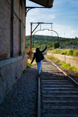 mujer con pantalón blanco paseando por las vías del tren