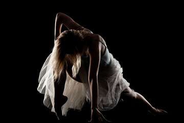 ballerina with a white dress and black top posing on black background. side lit silhouette. © Nikola Spasenoski
