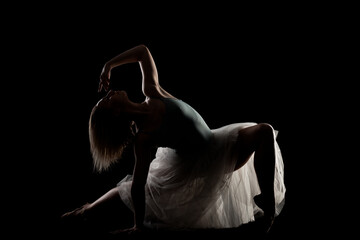 ballerina with a white dress and black top posing on black background. side lit silhouette. © Nikola Spasenoski