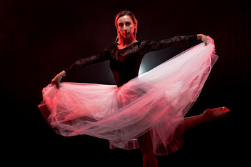 ballerina with a white dress and black top posing on red smoke background © Nikola Spasenoski