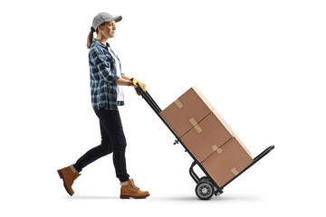 Full length profile shot of a woman pushing a hand truck with cardboard boxes
