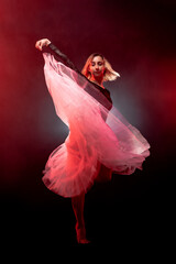 ballerina with a white dress and black top posing on red smoke background © Nikola Spasenoski