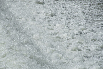 Close-up of the foaming white water of a stretch of the Isar River with a fast current in Munich, Germany, in springtime