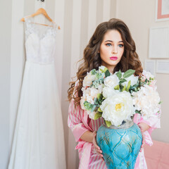 Morning of the bride in pajamas on the background of a wedding dress.