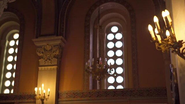Rotating shot of the internal environment of a Catholic church. Candles are burning on the shelves.