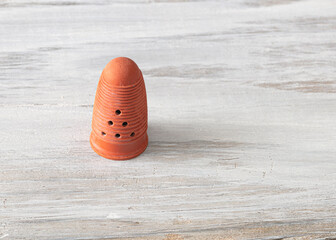 Small plastic cap worn on the finger to push the needle in sewing.