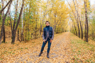 Fototapeta premium Tall handsome man walking in the autumn alley