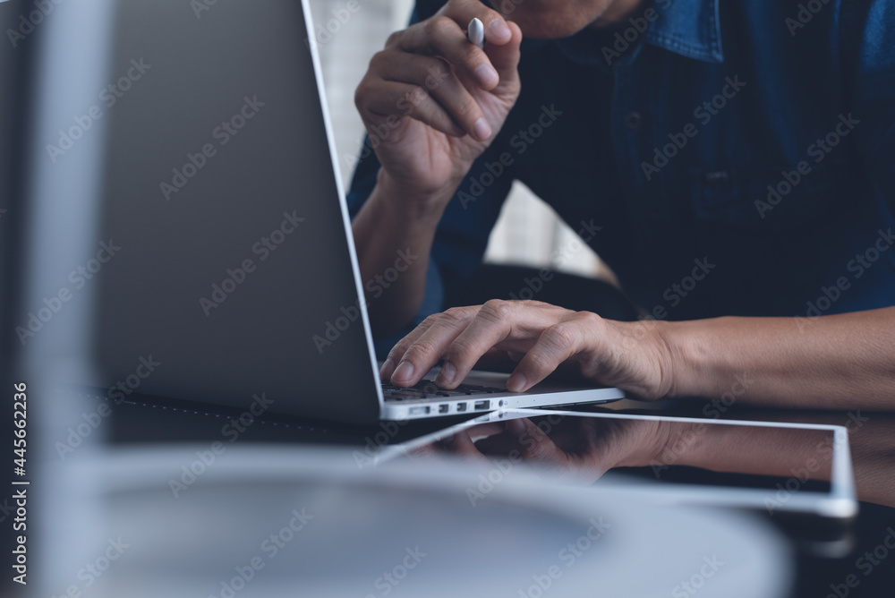 Poster man working on laptop computer and digital tablet on table at home office, work from home concept