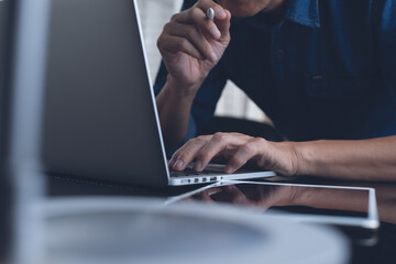 Man working on laptop computer and digital tablet on table at home office, work from home concept