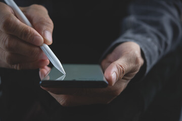 Business man using stylus pen signing on mobile phone and digital tablet, close up