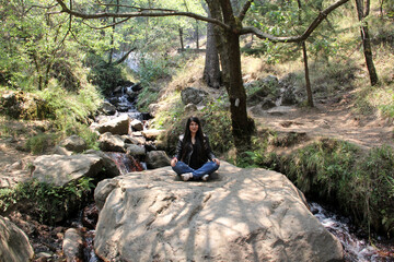 Fototapeta premium Young latin woman in the middle of the forest with rivers and waterfalls exploring and meditating 