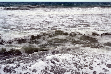 a view of the seething waves with foam during a storm at the sea, a view from the shore