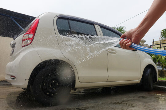 Cropped Hands Of Adult Washing Car. Image Focus on Hand and Water Pipe.