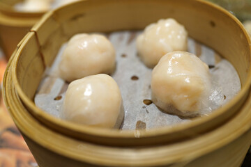 Soft focus image of Chinese dim sum dumpling stuffed with prawns in a bamboo steamer.