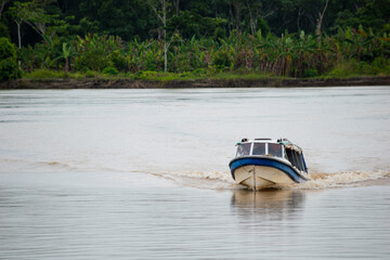 Boat navigating the Orinoco river with a background of green trees in San José Del Guaviare...
