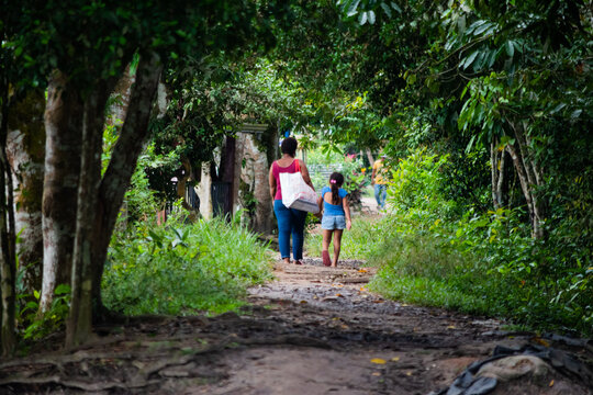Woman walking with her daughter along a path full of green trees