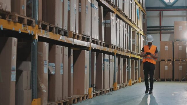 The worker inspects the goods in the warehouse. Warehouse manager enters data via tablet