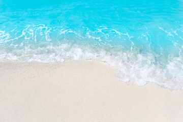 Sea wave and bubble on a sandy white beach blue sea background texture and copy space holiday concept