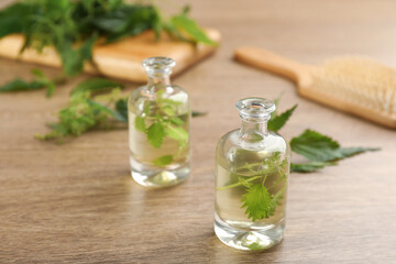 Stinging nettle extract and leaves on wooden background. Natural hair care