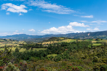 Fototapeta na wymiar Landscape of mountains, country houses and crops with a blue sky and some clouds in Colombia.