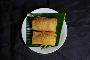 Fried spring rolls isolated on black background. This typical Semarang food which is sometimes spelled as “lun pia” is a kind of traditional Chinese-Javanese fusion of snacks. Focus blur. Snack mockup
