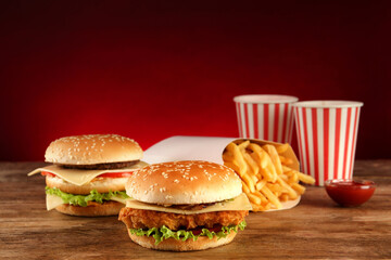 Delicious fast food menu on wooden table against red background