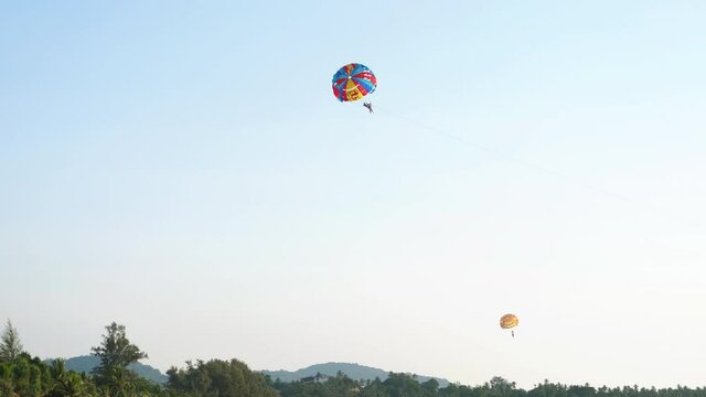 People parasailing behind speedboat at sea