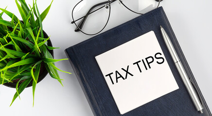Stickers on notebook text TAX TIPS with pen and glasses on white background
