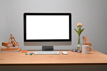 Modern workplace with computer and personal equipment on wooden desk.
