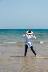 Cheerful tanned woman at beach enjoying nature-freedom. outdoor at tropical resort with her arms outstretched the wind. Beautiful young female enjoying day at ocean beach