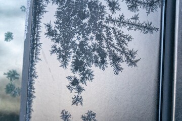 Selective focus. First frost on a frozen black plastic, late autumn close-up. Beautiful abstract frozen microcosmos pattern. Freezing weather frost action in nature. Winter backdrop.