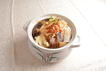 Chinese traditional luxury cuisine buddha jump over the wall with seafood abalone, sea cucumber, shark's fin, scallop and meat in hot herbal ginseng soup clay pot in white gold background asian menu