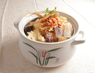 Chinese traditional luxury cuisine buddha jump over the wall with seafood abalone, sea cucumber, shark's fin, scallop and meat in hot herbal ginseng soup clay pot in white gold background asian menu