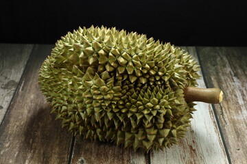 Whole of organic durian fruit isolated on the wooden floor. Famous King of fruit in Thailand. 