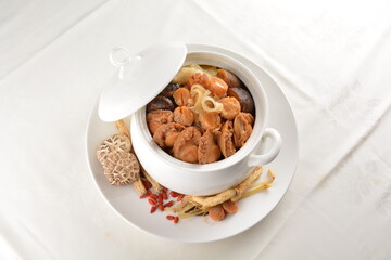 Chinese traditional luxury cuisine buddha jump over the wall with seafood abalone, sea cucumber, shark's fin, scallop and meat in hot herbal soup clay pot in white gold background asian menu for new y