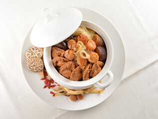 Chinese traditional luxury cuisine buddha jump over the wall with seafood abalone, sea cucumber, shark's fin, scallop and meat in hot herbal soup clay pot in white gold background asian menu for new y