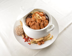 Chinese traditional luxury cuisine buddha jump over the wall with seafood abalone, sea cucumber, shark's fin, scallop and meat in hot herbal soup clay pot in white gold background asian menu for new y