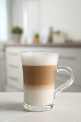Glass cup of delicious layered coffee on light marble table indoors, space for text
