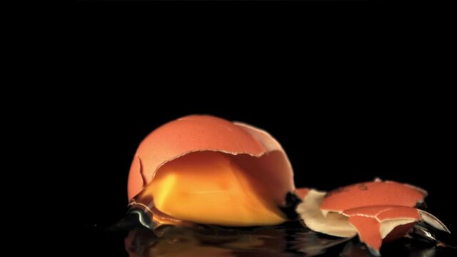 Super slow motion the fresh egg falls on the table and breaks down. On a black background.Filmed on a high-speed camera at 1000 fps.