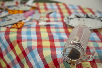 Closeup of a fallen coffee glass on a messy destroyed picnic table with a colorful checkered cloth