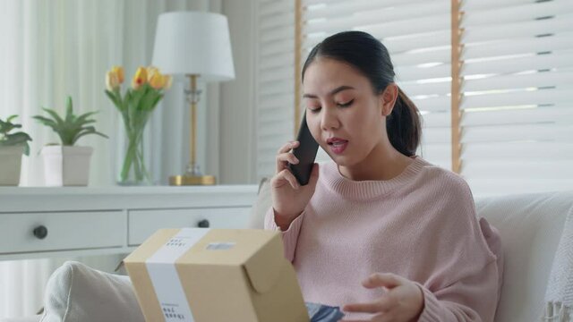 Upset mad asia people young girl consumer sit sofa at home open fake product order, damage post mail buy from online shopping retail store. Shock sad teen woman unbox from wrong bad shipping service.