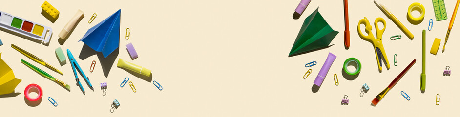 Top view of bright colorful various stationery on yellow pastel background. Back to school concept banner with place for text. Panoramic backdrop, copy space