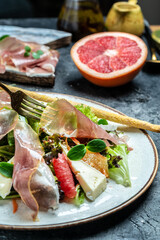 Prosciutto di Parma salad with grapefruit, salad mix, grapefruit, cherry tomatoes, parmesan cheese. Cold snacks. Restaurant menu, dieting, cookbook recipe