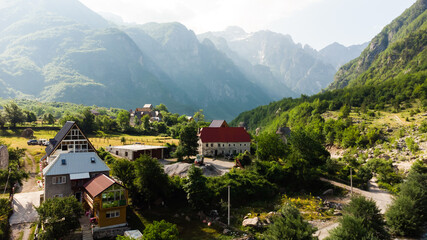 Beautiful view of the small and historic village of Theth with church and the surrounding mountains with green trees. Sunny late summer weather with blue sky. Theth National Park, Albania.
